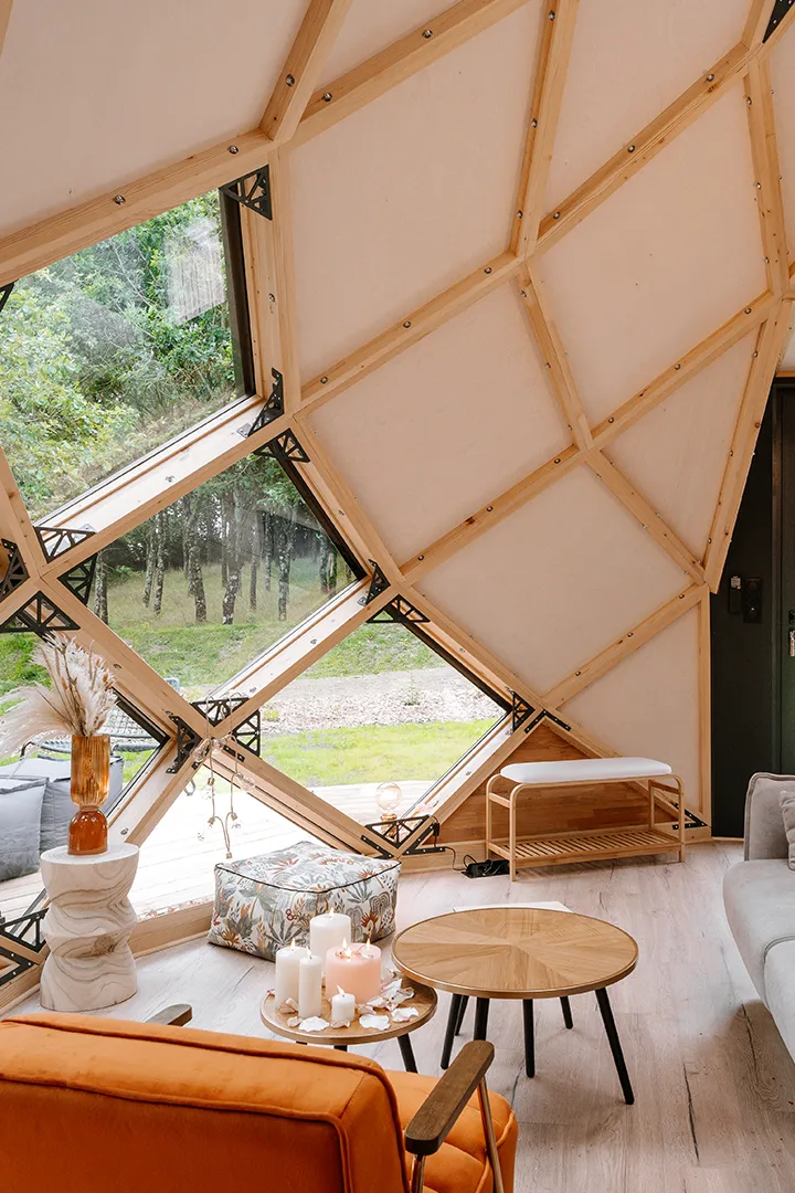 Intérieur Armadillo Evozome — zome habité, fenêtre triangulaire ouverte sur la forêt, mobilier chaleureux